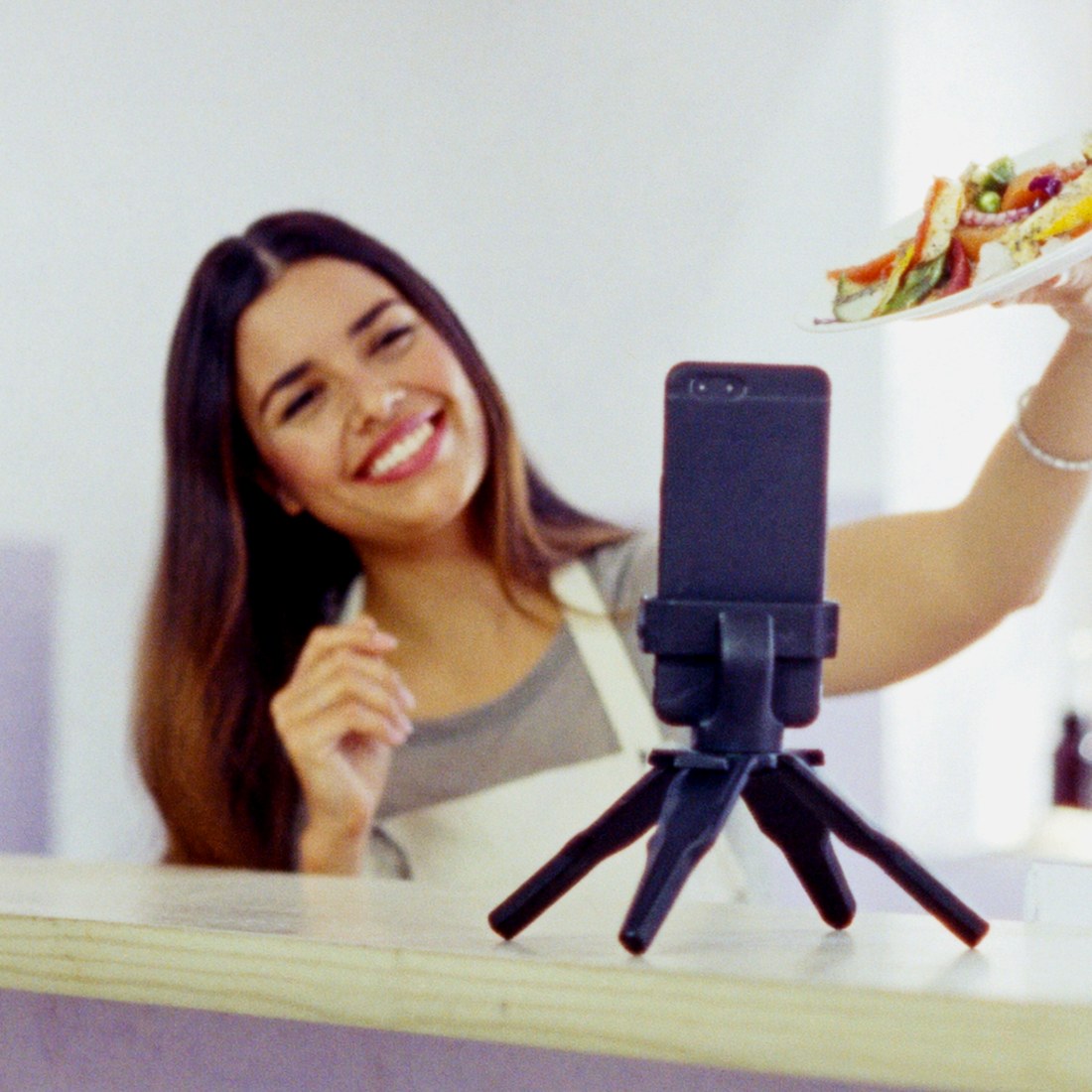 Owner of a neighbourhood restaurant showing a dish to her phone camera